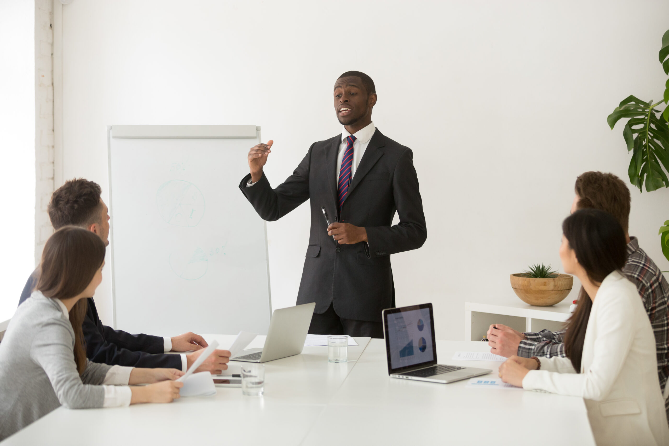 confident-african-speaker-business-coach-giving-presentation-team-scaled.jpg